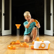 Child building an Air Toobz pathway with clear tubes and orange connectors